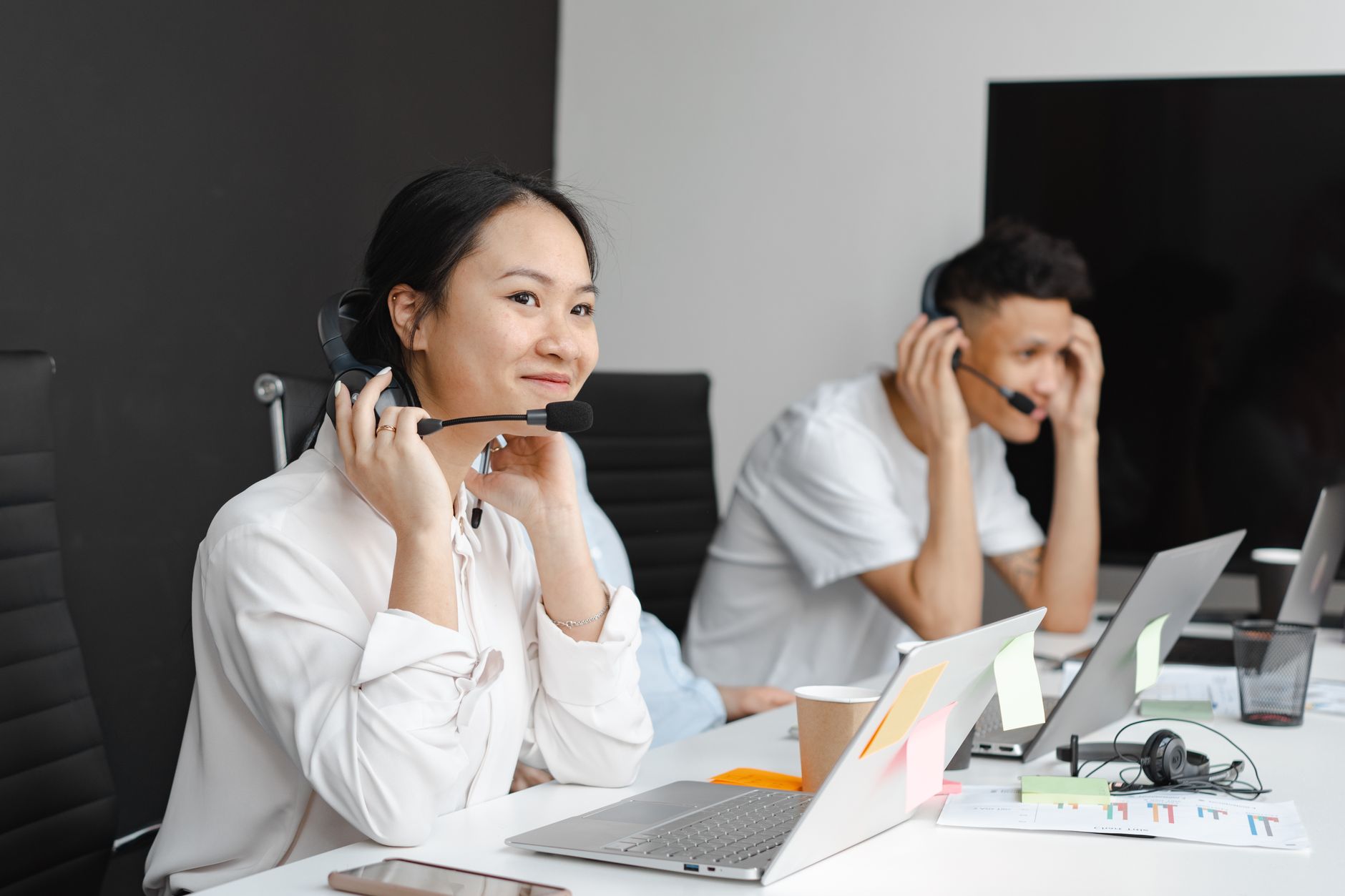 A professional support specialist in a modern office environment working on multiple screens with data visualisations and customer chat interfaces.