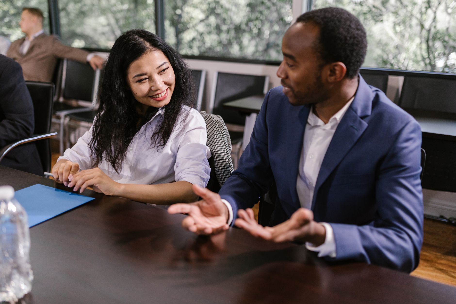 A professional manager in a modern office looking at a laptop screen featuring a video call with a diverse team of remote professionals.