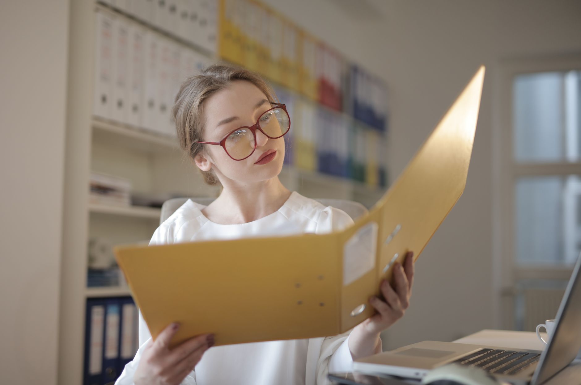 A professional finance specialist reviewing complex tax documents and digital spreadsheets in a modern office environment.
