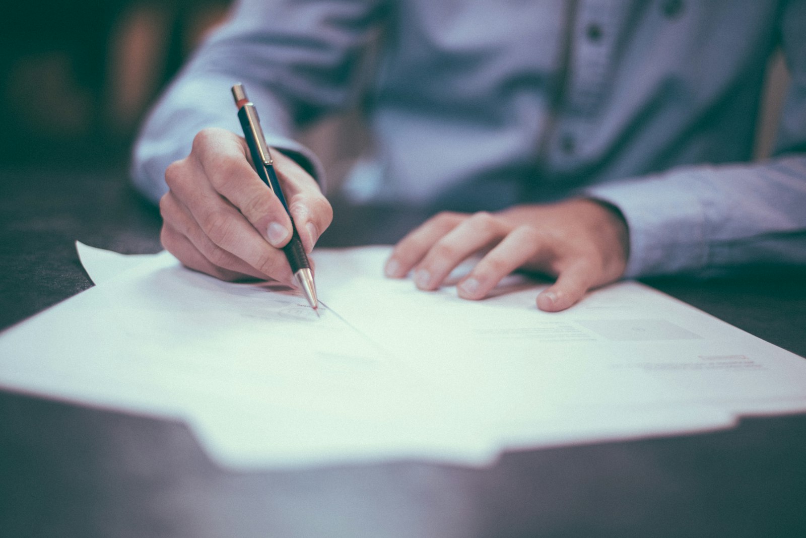 A person signing a contract at a wooden desk